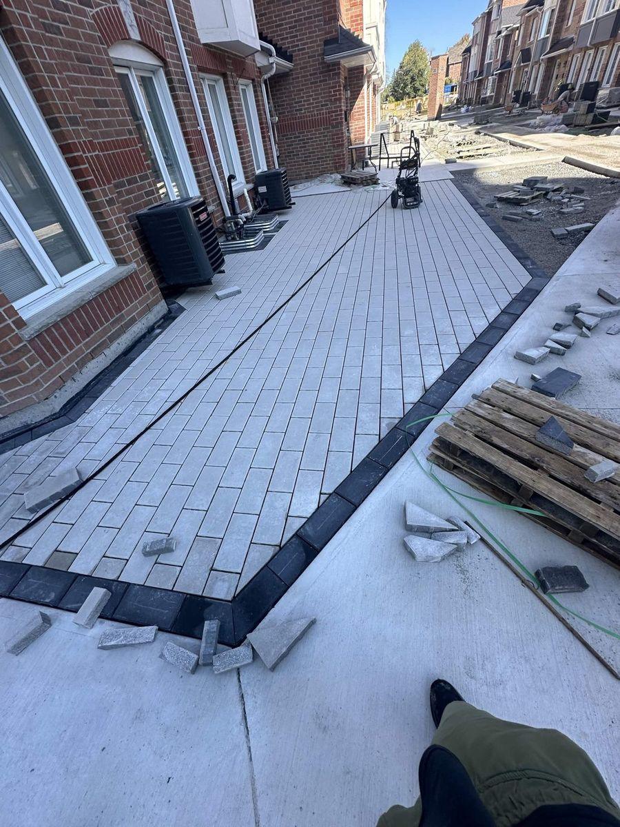 Interlock walkway with a dark border band being laid along the townhouse rows