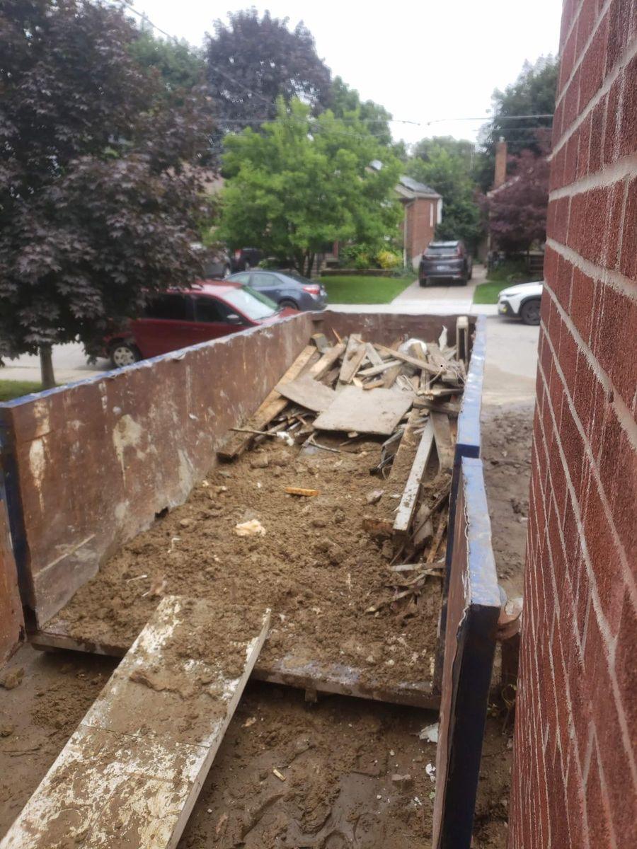 Bin of soil, wood and rubble beside a house