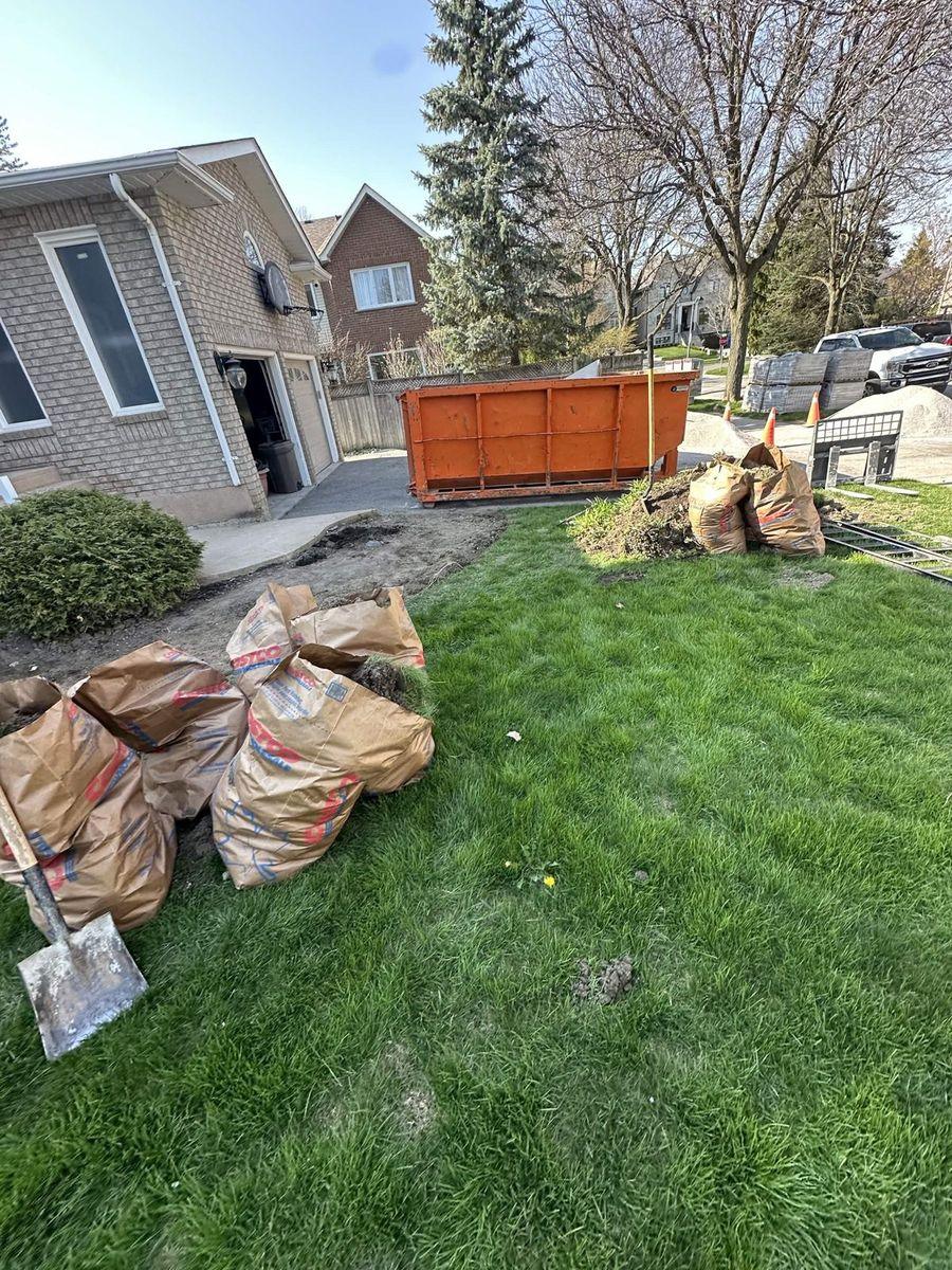 Yard waste bags on the lawn beside a bin, ready to go