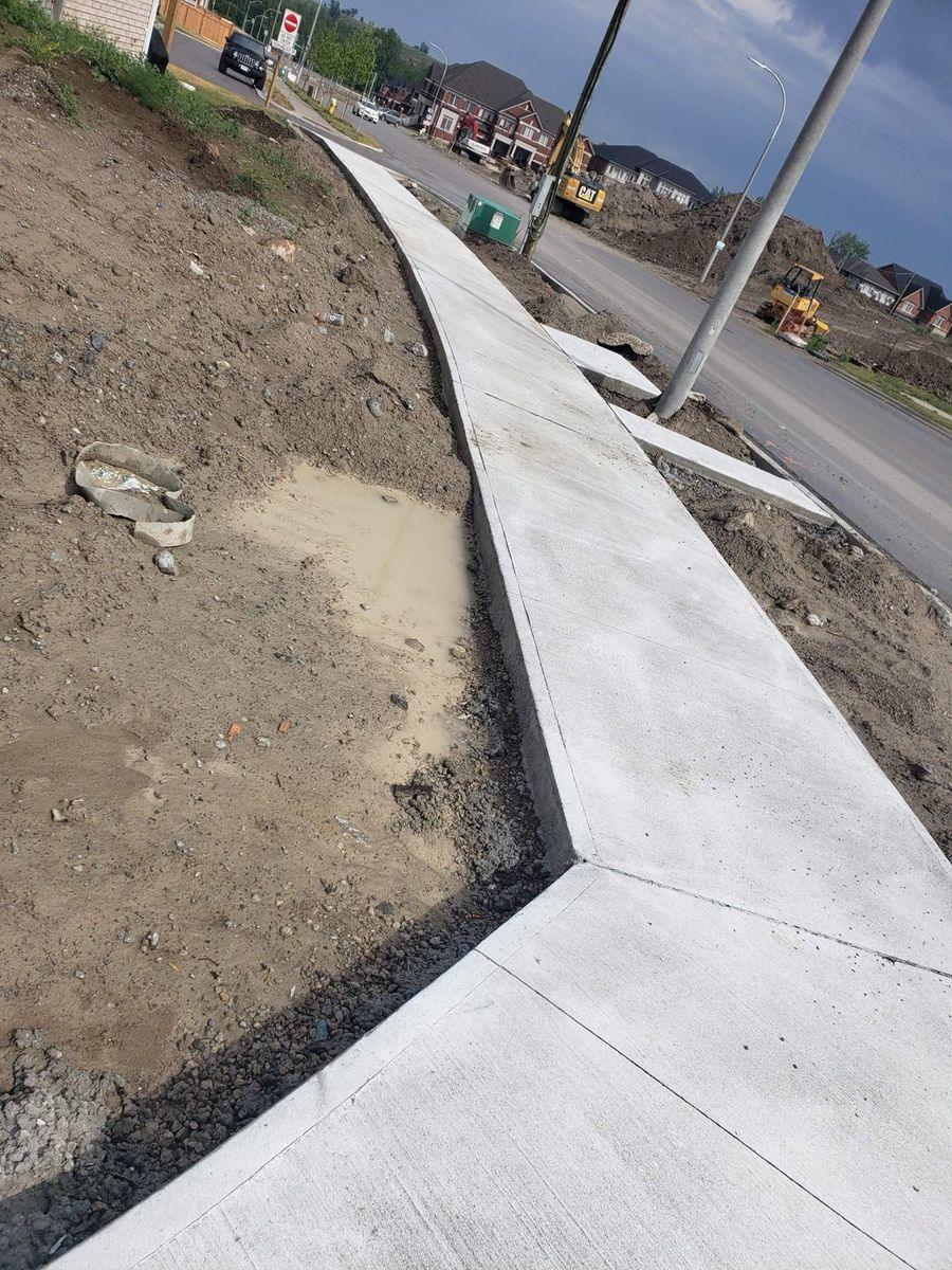 The finished concrete sidewalk curving along the road, June 14, 2021