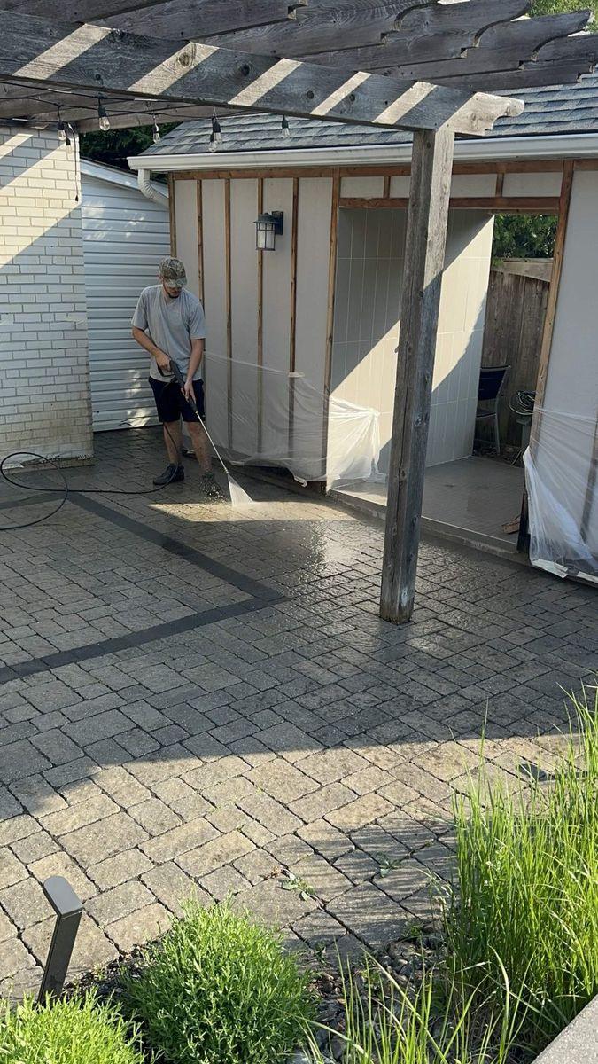 Crew member washing the interlock beside the pool shed