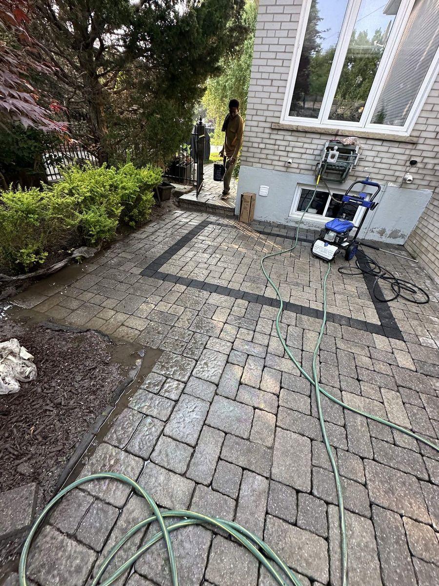 Side-yard interlock being washed, pressure washer by the house