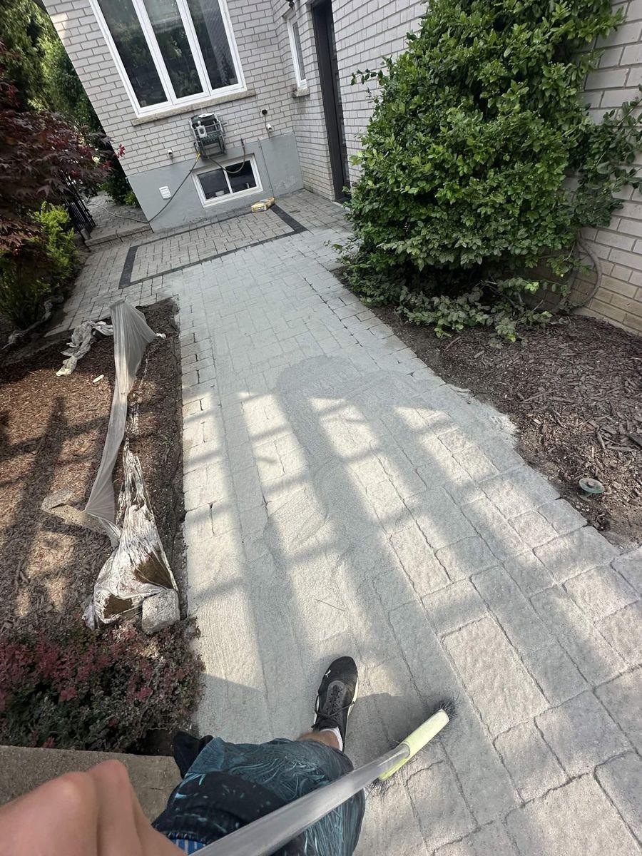 Side walkway mid-wash: clean lanes beside the dirty pavers